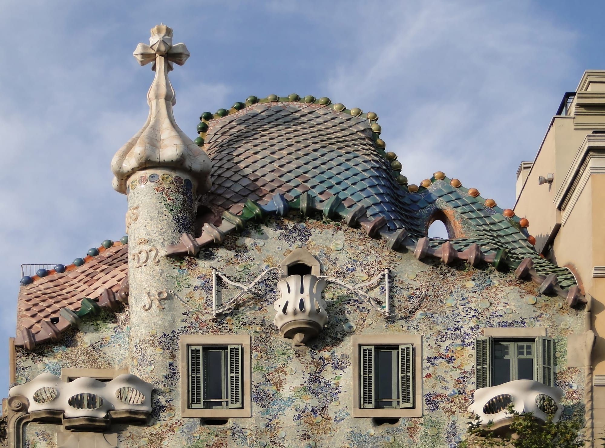 Gaudí's Casa Batlló: the scaly dragon-back roof, cross-topped turret and mosaic-covered upper façade against a blue sky